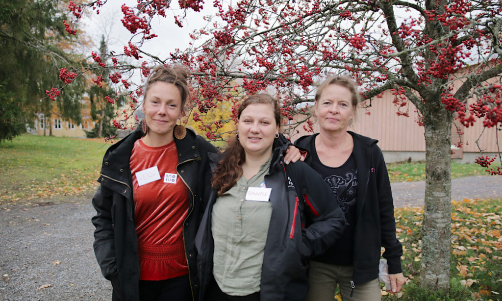 Hannele Tiitto, Jenni Lahtonen ja opettaja Helena Ahonen seisovat ruskamaisemassa pihlajan luona.